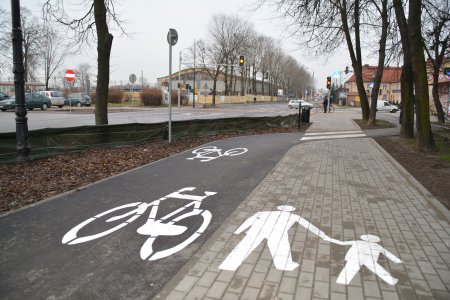 Chodnik i ścieżka rowerowa wzdłuż ul. Sienkiewicza. Chodnik z betonowej kostki, oznakowany namalowanym na nawierzchni schematycznym rysunkiem dorosłego z dzieckiem trzymanym za rękę. Ścieżka oznakowana namalowanym na nawierzchni rowerem