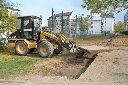 Ciągnik z widlakiem usuwa betonowe płyty z miejsca, w którym powstanie nowy, równy chodnik z betonowej kostki