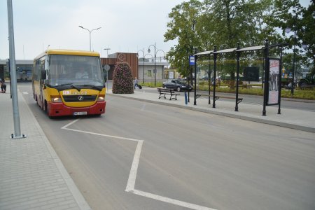 Autobus komunikacji miejskiej stoi na przystanku przed dworcem kolejowym