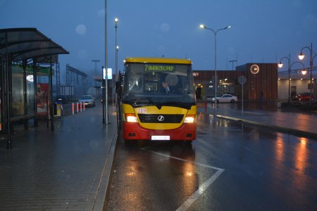 Zdjęcie wykonane po zmroku. Na przystanku autobusowym przy dworcu PKP stoi autobus linii nr 7