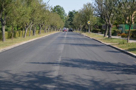 Nowa nawierzchnia ulicy Gostkowskiej. Po obu stronach drogi rosną drzewa. W oddali widać dwa mijające się samochody i jadącego rowerzystę