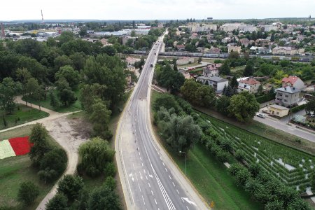 Zdjęcie wykonane z góry. Ulica Płocka z wiaduktem. Po lewej stronie park Marii Konopnickiej a w nim rabata kwiatowa w kształcie terytorium Polski, w barwach flagi narodowej. Po prawej stronie ulicy Płockiej widać zielony labirynt 