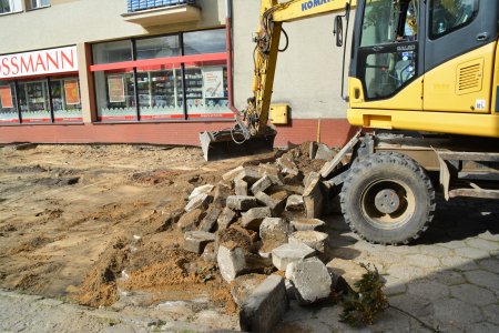 Koparka zrywa betonowe elementy pokrywające teren za sklepem Rossmann. Część betonowych kloców została wykopana. Odkryto ziemię