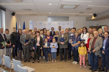 Grupowe zdjęcie w sali konferencyjnej Urzędu Miasta. Na zdjęciu nagrodzeni uczestnicy konkursu na najładniejsza posesję oraz prezydent Ciechanowa Krzysztof Kosiński i kilkoro urzędników. Na pierwszym planie trójka dzieci