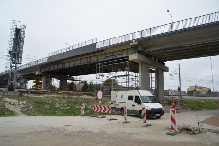 Wiadukt nad torami. Pod wiaduktem rusztowania. Obok ulica zagrodzona barierkami zabezpieczającymi. Za barierkami stoi auto dostawcze