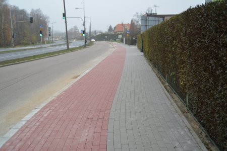 W kadrze długi chodniki i ścieżka dla rowerów wybudowane wzdłuż jezdni