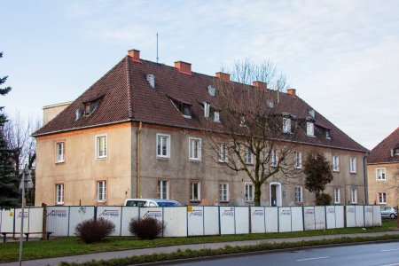 Jednopiętrowy blok ze spadzistym dachem i zamieszkałym poddaszem. W dachu widać tzw. 