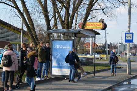 Przystanek autobusowy z nową, zadaszoną wiatą. Na przystanku dużo młodzieży. onad wiatą widać logo sklepu Biedronka. W głębi po lewej widać fragment ściany sklepu, a po lewej część ul. Tatarskiej