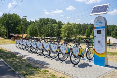 Stacja rowerowa przy kąpielisku Krubin. Po prawej stronie stacji jest terminal, który na górze ma zamontowany panel słoneczny.