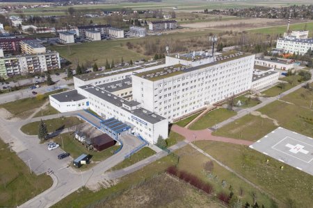 Szpital w Ciechanowie z wysoka. Ujęcie od strony skrzyżowania z ulicą Pułtuską. Budynek szpitala zajmuje środkową część kadru. Po prawej stronie, blisko rogu kadru, jest lądowisko dla helikopterów. Po lewej u góry, ponad zabudowaniami szpitala są bloki sąsiedniego osiedla 