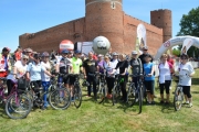 Pamiątkowe zdjęcie - grupa rowerzystów z prezydentem Ciechanowa (także w sportowym stroju, kasku i z rowerem) na tle Zamku Książąt Mazowieckich