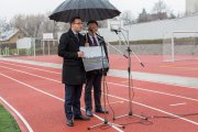 Konferencja prasowa. Przy mikrofonie K. Kosiński, obok A. Struzik. Prezydent Ciechanowa pokazuje dużą fotografię bieżni i boiska, zrobioną przed wybudowaniem kompleksu sportowego - na zdjęciu zniszczona murawa i zabłocona bieżnia