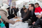 Prezydent Ciechanowa i jego pomocnicy (jeden w mikołajowej czapce) częstują ludzi kapustą i pierogami