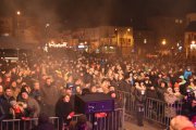 Ludzie zgromadzeni na placu wspólnie czekają na nadejście nowego roku. Zdjęcie zrobione ze sceny. Widać balustrady oddzielające widownię od sceny oraz sprzęt oświetleniowy