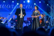 Trwa koncert. Bogusław Morka śpiewa. Obok stoi Iwona Kaczmarek. W tle widać grającą orkiestrę kameralną Alla Vienna