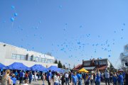 Niebieskie balony na tle nieba osiągnęły już znaczną wysokość. Zgromadzeni na placu przed halą sportową śledzą ich lot