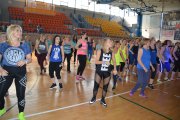 W hali sportowej duża grupa uczestniczek Maratonu Zumba Fitness wykonuje ćwiczenia