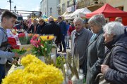 Stoisko z kwiatami: żonkile, tulipany, kaktusiki w doniczkach. Stoisko obsługuje chłopiec. Trzyma w ręku tulipany i słucha zamówienia składanego przez jedną z trzech osób stojących przed stoiskiem.