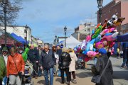 Ludzie oglądający ofertę kramarzy. Obok na stojaku balony