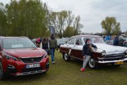 Wiele aut zaparkowanych na błoniach w pobliżu Zamku Książąt Mazowieckich. Po prawej dwukolorowe dawne auto z oldskulową linią, po prawej nowoczesne