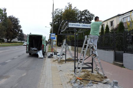 Pracownik montuje nową wiatę przystankową miejskiej komunikacji