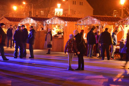 Ubiegłoroczny Jarmark Bożonarodzeniowy, wieczór, rozświetlone stragany na Pl. Jana Pawła II, przed nimi ludzie spacerujący lub oglądający prezentowane towary