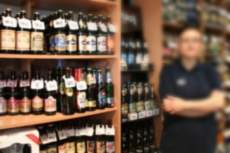 Sklepowy regał, na którym stoją butelki z alkoholem