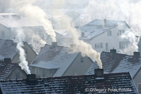 Dachy domów z bardzo dymiącymi kominami. W prawym dolnym rogu nazwisko autora zdjęcia: Grzegorz Polak i oznaczenie portalu, z którego pochodzi zdjęcie: fotolia