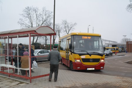 Autobus miejskiej komunikacji podjeżdża do przystanku. Na przystankowej ławce siedzi kilku pasażerów