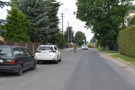 Ulica Bony. W miejscu wykopów położony został pas nowego asfaltu. Po lewej stoją zaparkowane dwa samochody osobowe