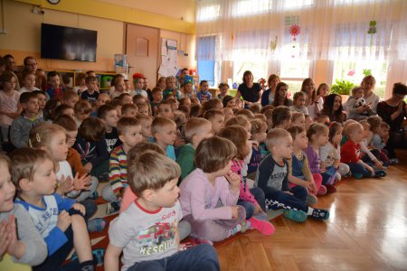 Sala przedszkolna wypełniona dużą grupą dzieci siedzących na podłodze