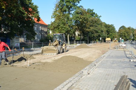 Fragment ul. Sienkiewicza. Po lewej nowy chodnik z kostki, po prawej trwa przygotowywanie podbudowy pod jezdnię. Na placu budowy stoi koparko-ładowarka