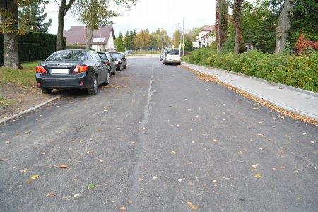 Ulica Bema z nową, równą nawierzchnią. Po lewej stronie, częściowo na jezdni, częściowo na trawniku parkuje kilka samochodów. W oddali widać kilka aut zaparkowanych po prawe stronie wzdłuż chodnika