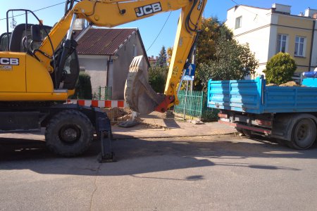 Ciężki sprzęt rozpoczął prace na ul. Ułańskiej. Na pierwszym planie duża koparka i samochód z przyczepą, na którą ładowany jest nadmiar ziemi