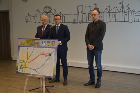 Konferencja prasowa. Przedstawiciele trzech samorządów prezentują tablicę z zaznaczonym przebiegiem planowanej drogi