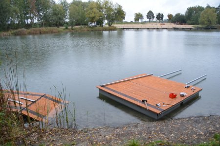 Zbiornik wodny na Krubinie po przeciwnej stronie plaży. Wzdłuż brzegu montowane są drewniane kwadratowe elementy podestów.