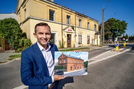 Prezydent Krzysztof Kosiński stoi na tle kamienicy przy ulicy Fabrycznej 2. W dłoniach trzyma wydruk z projektu, na którym znajduje się budynek po rewitalizacji.