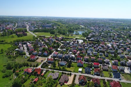 Ciechanów z wysoka. Po lewej stronie fotografii znajduje się Zamek Książąt Mazowieckich i zamkowe błonia. Środek i prawą stronę zdjęcia zajmuje osiedle domów jednorodzinnych.