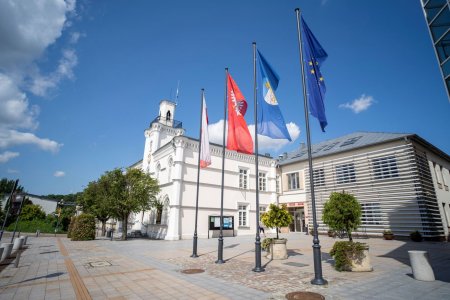 Ciechanowski ratusz. Zdjęcie zrobiono od strony Urzędu Stanu Cywilnego. Po prawej stronie ratusza stoją cztery maszty z flagami: Polski, województwa mazowieckiego, z herbem Ciechanowa i unijna.