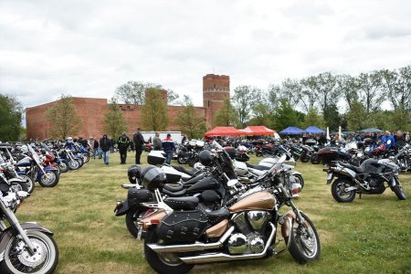 Na pierwszym planie zdjęcia stoi zaparkowanych wiele motocykli. Śmiało można oszacować, że jest ich ponad sto. W głębi znajduje się Zamek Książąt Mazowieckich oraz namioty i stoiska.