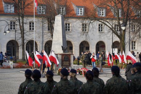 Ubiegłoroczne obchody Święta Niepodległości na placu Marszałka Piłsudskiego. Po obu stronach monumentu poświęconego Marszałkowi, stojącego pośrodku placu, ustawiono biało-czerwone flagi. Wartę sprawują mundurowi z różnych formacji wojskowych i szkół mundurowych. W tle znajduje się Krzywa Hala, znana ze swojej ciekawej, zakrzywionej budowy i krużganków.