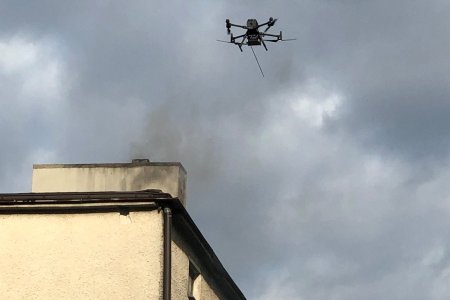 Dron wznoszący się przy dymiącym kominie.