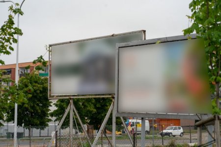 Dwie duże tablice reklamowe, umieszczone na metalowych stojakach. Znajdują się w miejskiej przestrzeni publicznej. Plakaty umieszczone na obu tablicach są rozmyte. Nie można dowiedzieć się czego dotyczą.