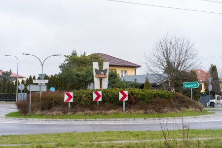 Rondo Solidarności. Na środku ronda znajduje się monument, złożony z dwoch betonowych płyt ustawionych na kształt litery V, tworzących solidarnościowy znak Victoria. Na tym znaku znajduje się logo Solidarności - czerwony, stylizowany napis SOLIDARNOŚĆ z biało-czerwoną flagą nad literą N. Rondo porastają krzewy. Za rondem znajdują się domy jednorodzinne. Na zjeździe w prawo stoi zielony znak drogowy wskazujący kierunek na Gąsocin.