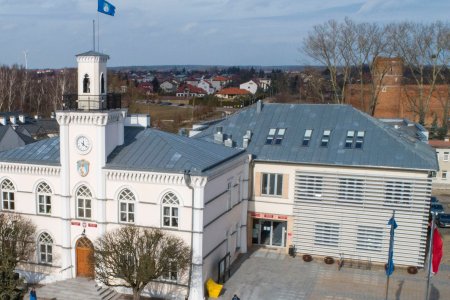 Zdjęcie ratusza, wykonane z wysoka. Po prawej stronie zabytkowego magistratu stoi dobudowana, nowsza część obiektu, w której mieści się Urząd Stanu Cywilnego. W głębi zdjęcia, za ratuszem po prawej znajduje się Zamek Książąt Mazowieckich, a dalej osiedle domów jednorodzinnych.