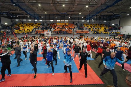 Wielu zawodnikow taekwon-do ćwiczy układy kata we wnętrzu hali sportowej.