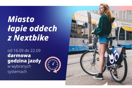 Grafika składająca się z napisu i zdjęcia. Po lewej znajduje się napis wykonany białymi literami na granatowym tle: Miasto łapie oddech z Nexstbike od 16 do 22 września; darmowa godzina jazdy w wybranych systemach. Po prawej stronie grafiki znajduje się zdjęcie młodej kobiety z rowerem. Dziewczyna ma długie jasne włosy, ubrana jest w bluzę i krotkie dżinsowe spodenki. W tle żołto szaro niebieski tramwaj.