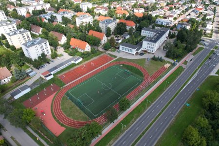 Szkoła Podstawowa nr 6 i przyszkolny kompleks sportowy. Dookoła bloki i domy jednorodzinne. Na dole kadru biegnie dwupasmowa ulica Tatarska. Szkolny kompleks sportowy składa się z boiska do piłki nożnej, bieżni, placu zabaw i plenerowej siłowni oraz dwoch boisk wielofunkcyjnych.